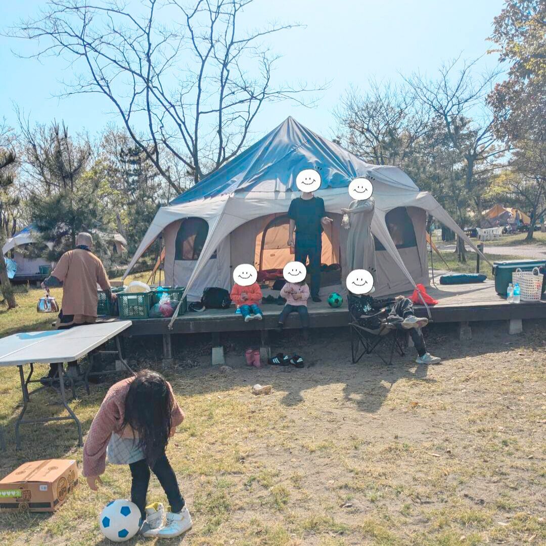 ベージュの大きなテントの前で座って飲み物を飲んだり、お話をしたりしている６人の子どもたちの様子