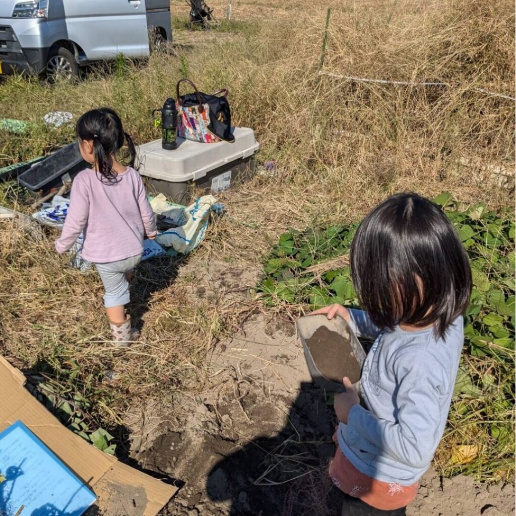 畑の周りを歩き回って砂遊びをする２人のこどもの写真