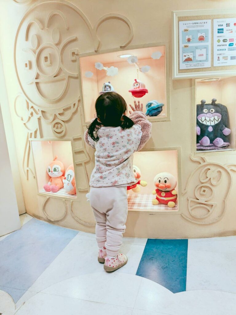 アンパンマンミュージアムのキャラクターを見ている２歳の女の子の後ろ姿の写真。