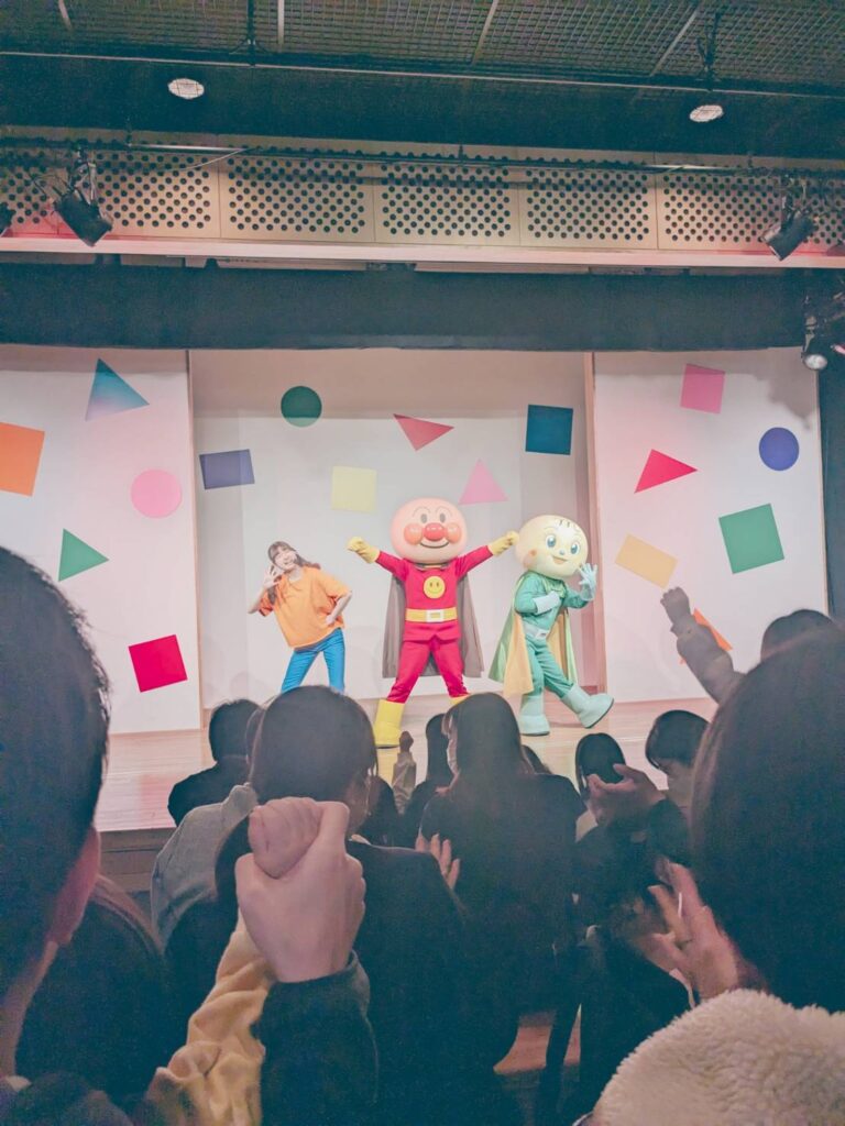 アンパンマンとメロンパンナちゃんとお姉さんがステージに立っている写真。